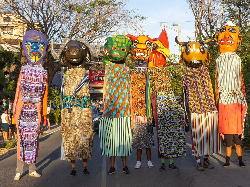 Colorful giant puppet figures in traditional Costa Rican masks and costumes lined up on a street during a community festival in Playa Flamingo, Guanacaste, Costa Rica