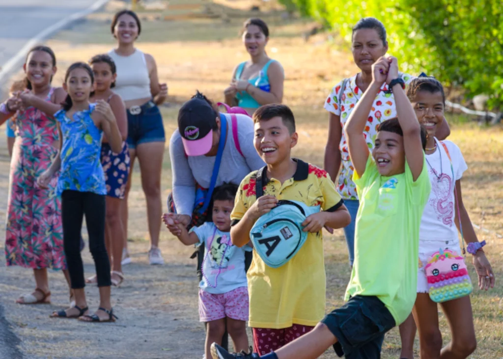 Playa Flamingo community members, including children and families, smiling and celebrating together outdoors, Guanacaste, Costa Rica