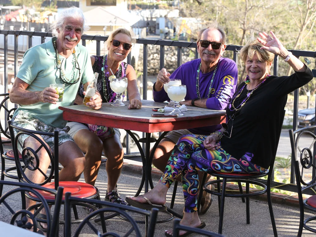Playa Flamingo community members enjoying drinks together at an outdoor table during a Mardi Gras celebration, Guanacaste, Costa Rica